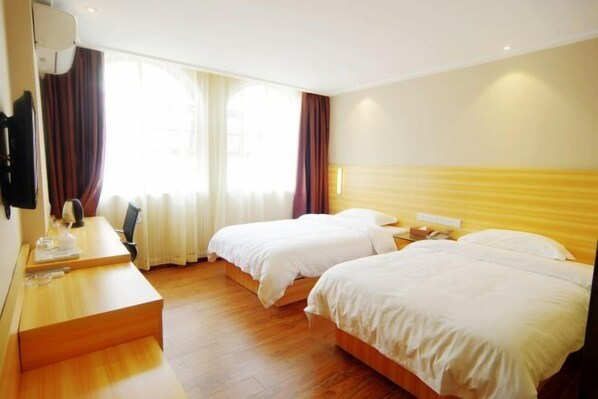 Habitación de hotel con dos camas, un escritorio y una ventana con cortinas.
