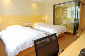 Habitación de hotel con dos camas, cabecero de madera, escritorio y cabina de ducha de vidrio.