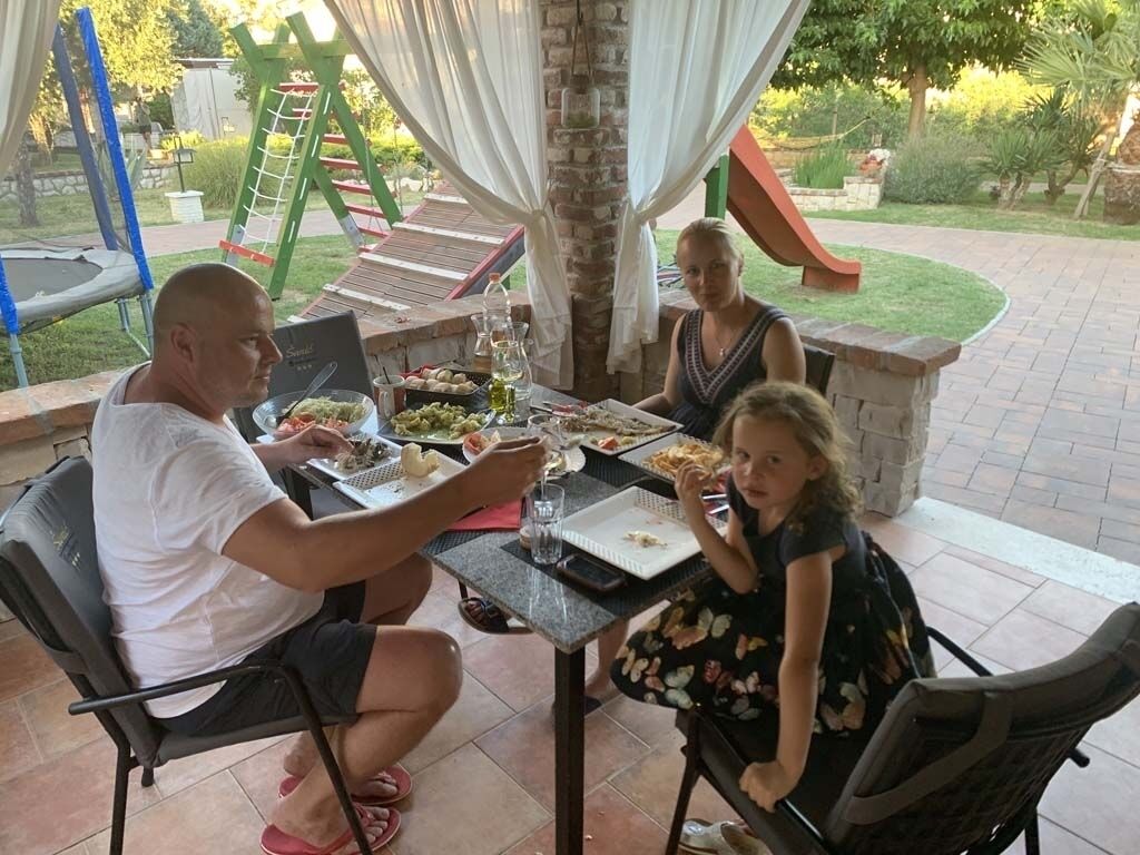 A patio dining area with a table set for four, surrounded by greenery and a slide.