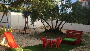 A playground with a slide, red plastic chairs, and a small table with a green cushion. - Apartment in Okrug Gornji with Seaview, Balcony, Air condition, WIFI (5048-5) (Okrug Gornji)