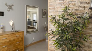 Ein Zimmer mit einem Holzschrank, einem Spiegel, einer Steinwand und einer Bambuspflanze.