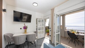 A modern room with a dining area, a flat-screen TV, and a balcony with a view of the sea. - Apartment in Okrug Gornji with Seaview, Air condition, WIFI, Washing machine (5049-1) (Okrug Gornji)