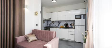 Una cocina moderna con armarios blancos, un salpicadero de mármol y un horno empotrado.