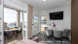 A modern room with a balcony, a dining area, and a TV mounted on the wall. - Apartment in Okrug Gornji with Seaview, Balcony, Air condition, WIFI (5049-2) (Okrug Gornji)