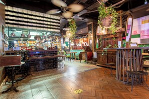 A restaurant interior with brick walls, wooden flooring, hanging plants, and a central seating area with tables and chairs. - Anjeliq Downtown Hotel (Alanya)