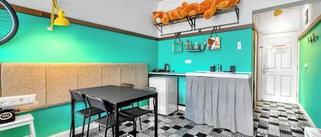 Eine kleine Küche mit Essbereich, einem Kühlschrank und einem Tisch mit Stühlen.