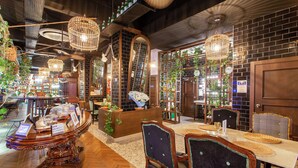 A restaurant interior with wooden furniture, hanging lights, and potted plants. - Anjeliq Downtown Hotel (Alanya)