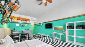 Una habitación con cama, escritorio, silla, televisor y ventilador de techo.