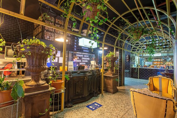 A restaurant with a brick wall, a signboard, and a hanging plant.