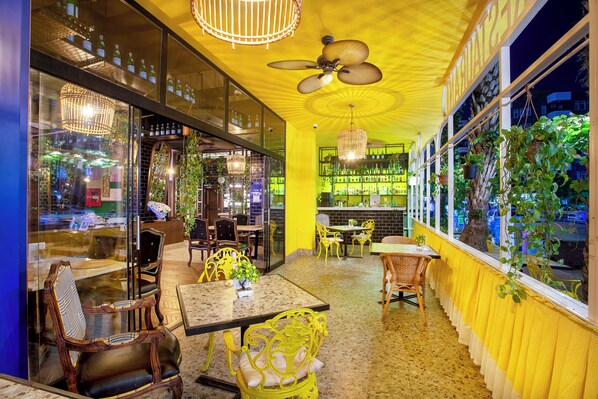 A restaurant with yellow walls, wooden furniture, and hanging plants. - Anjeliq Downtown Hotel (Alanya)