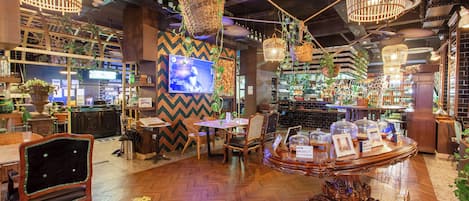 Ein Restaurant mit Holzböden, hängenden Korbwannen mit Pflanzen, einem Fernseher und einer Bar mit Flaschenregalen.