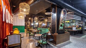 Un café acogedor con sillas de mimbre, un sofá verde y una zona de bar con taburetes.