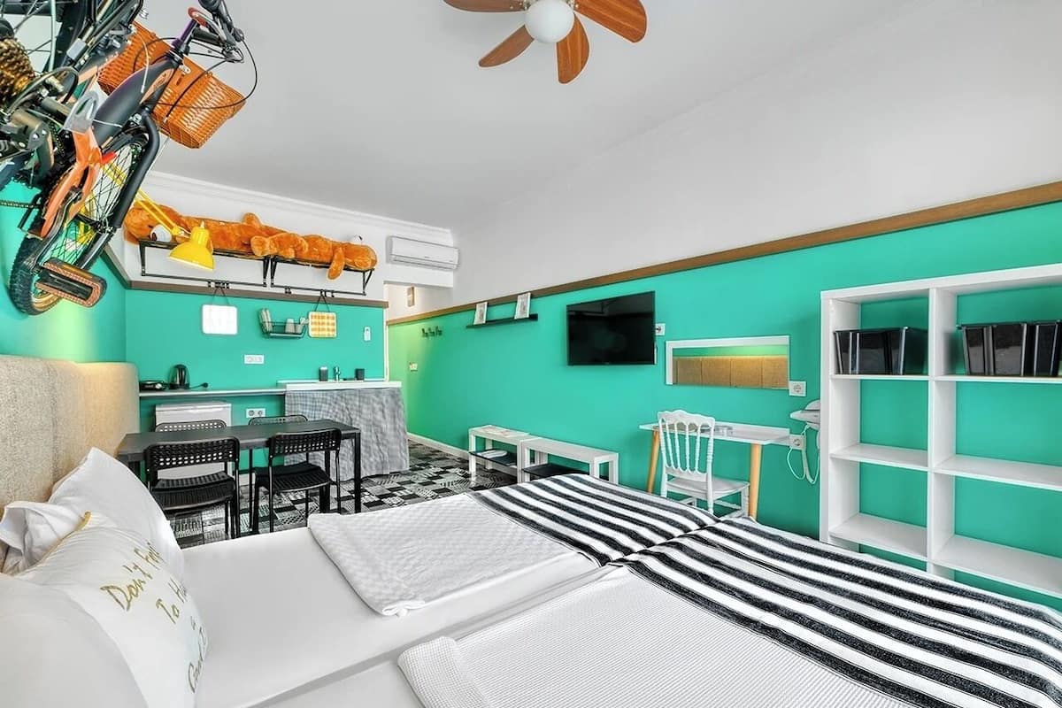 A room with a bed, a desk, a chair, a TV, and a ceiling fan.