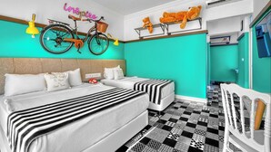 Habitación de hotel con pared de acento color aguamarina, cama con ropa de cama a rayas, bicicleta colgada en la pared y ventilador de techo.