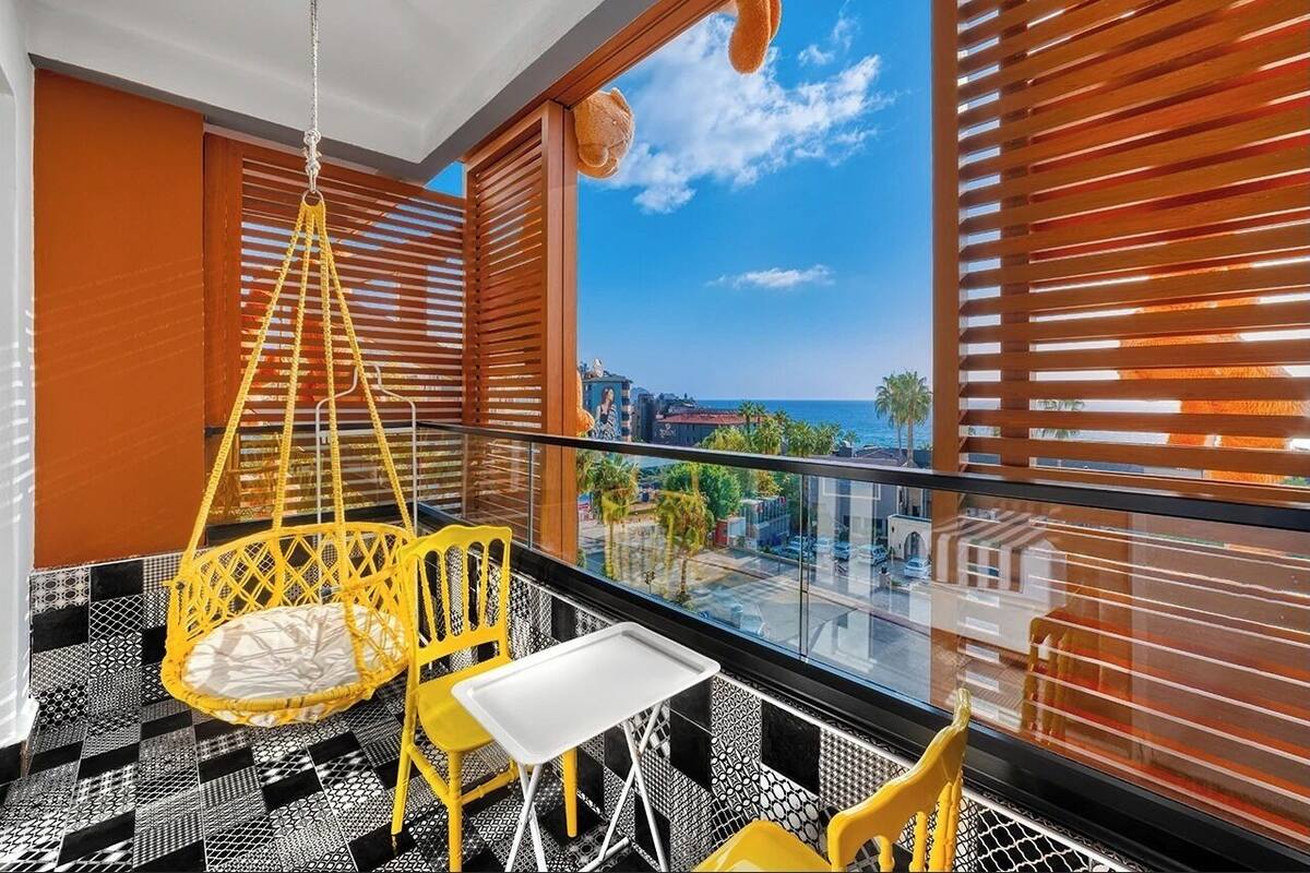 A balcony with a hanging chair, a small table, and two chairs.