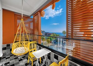 A balcony with a hanging chair, a small table, and two chairs.