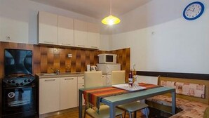 Une cuisine de taille réduite, avec des meubles blancs, un four à micro-ondes, une cuisinière et une table à manger avec des chaises.