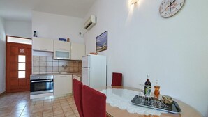 A compact kitchen with a dining area, including a table with a placemat and a few bottles. - Apartment in Trogir with Seaview, Balcony, Air condition, WIFI (5055-2) (Trogir)