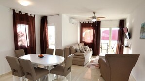 Ein modernes Wohnzimmer mit einem runden Esstisch, einem beigen Sofa und einem Deckenventilator.