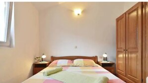 A bedroom with a bed, nightstands, a wooden wardrobe, and a wall-mounted light fixture.