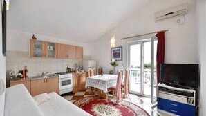 A compact living space with a kitchenette, a dining area, and a TV.