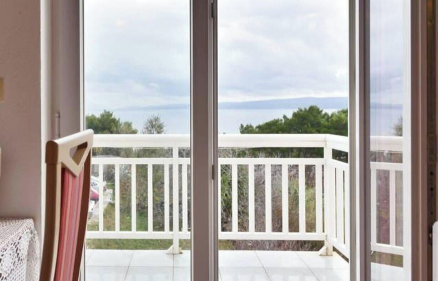 Un balcone con ringhiere bianche e vista su un cielo nuvoloso e un paesaggio lontano.
