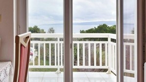 A balcony with white railings and a view of a cloudy sky and distant landscape.