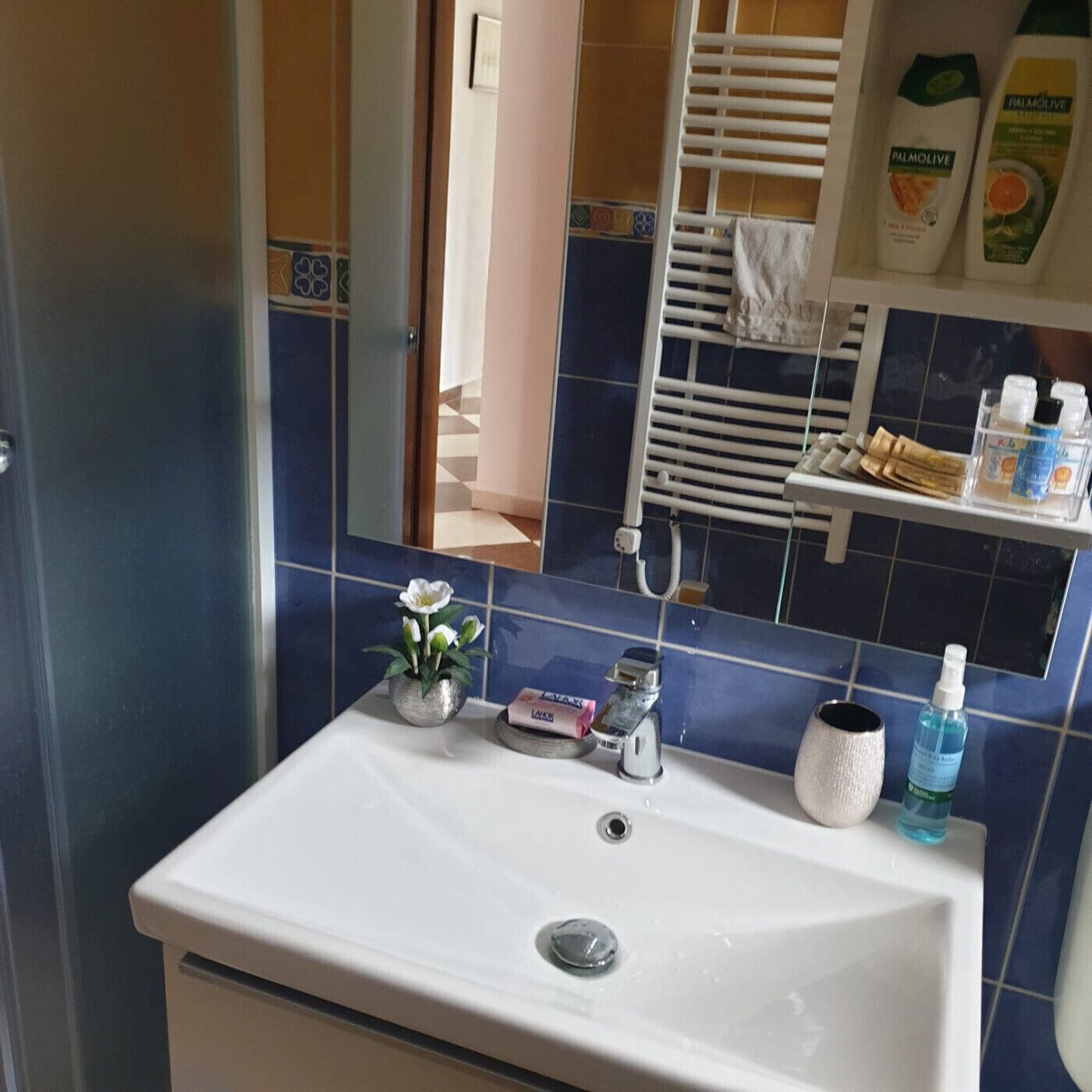 Une salle de bain avec un lavabo blanc, un miroir et un porte-serviettes.