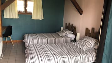 A bedroom with two beds, a chair, and a window with curtains.