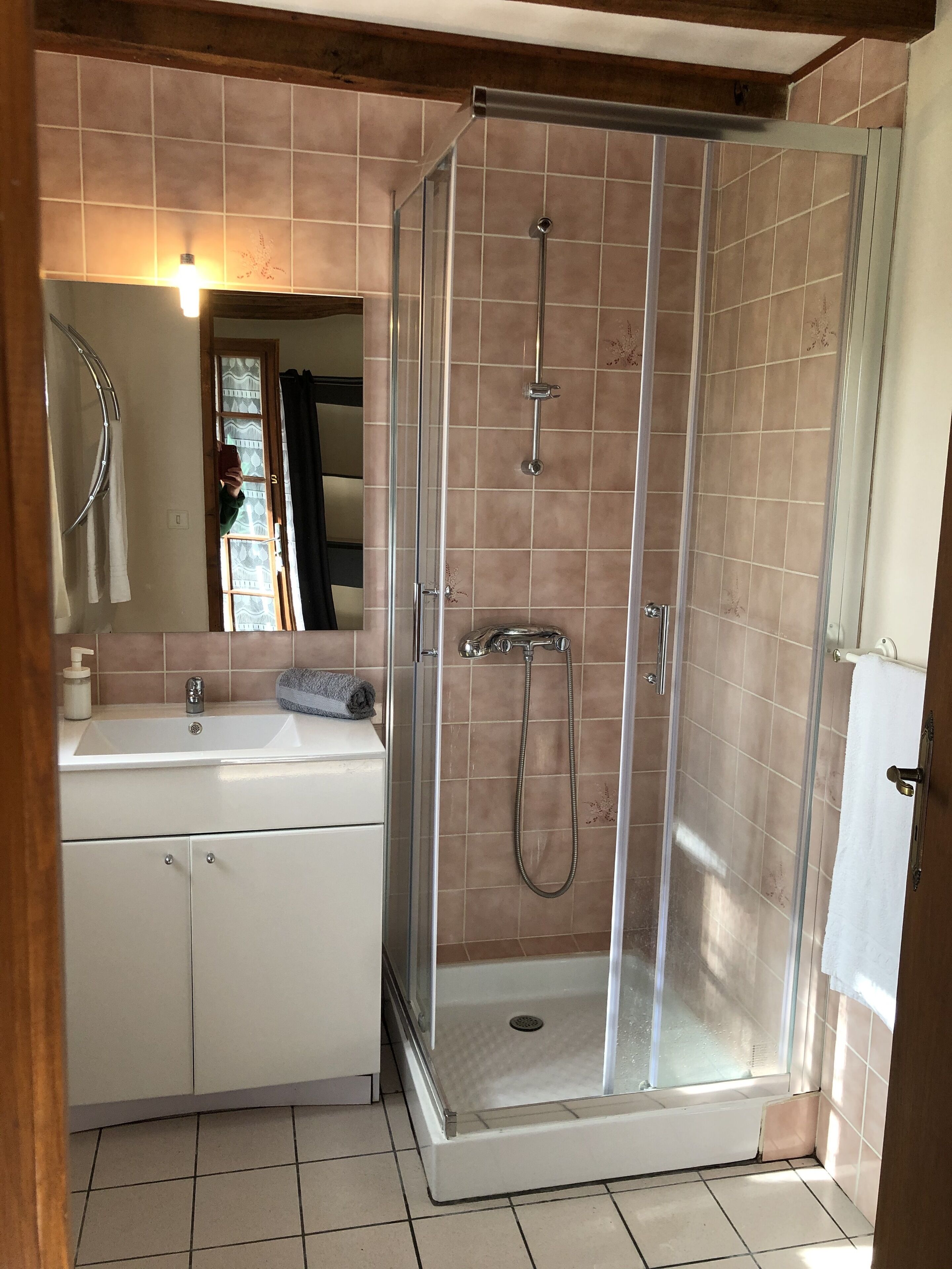 Un baño con ducha de vidrio, lavamanos y espejo.