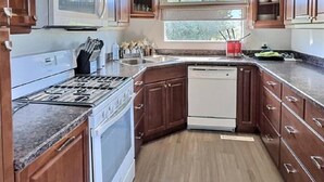 A kitchen with wooden cabinets, a stove, a dishwasher, and a window providing natural light. - 3 Bedroom Cottage at Delaronde Resort (Big River)
