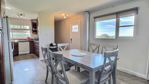 A modern kitchen with a dining area, a view through a window, and a door leading to another room. - 3 Bedroom Cottage at Delaronde Resort (Big River)