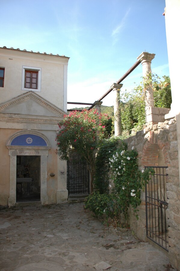 A building with a classical facade, a stone wall, and a metal gate.