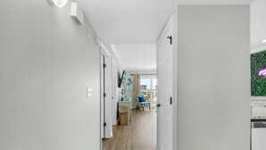 Un pasillo con paredes blancas y suelo de madera, que conduce a una habitación con vistas a la ciudad.