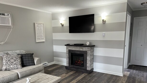 A living room with a fireplace, a sofa, a coffee table, and a flat-screen TV mounted on the wall. - Adventure Acres- Suite C5 (Holly)