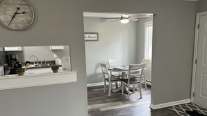 A modern kitchen with a clock, a dining area with chairs, and a ceiling fan. - Adventure Acres- Suite C5 (Holly)