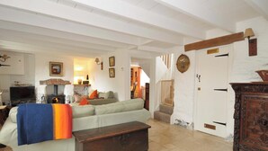 A living room with a sofa, a wooden bench, a fireplace, and a staircase leading to another room. - Island House (Fowey)