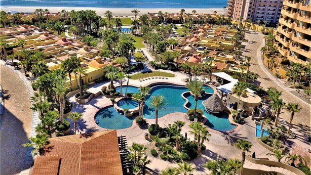 A resort with multiple swimming pools, palm trees, and beachfront views.