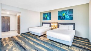 A hotel room with two beds, a large window, and abstract art on the wall. - La Quinta Inn & Suites by Wyndham Galveston North at I-45 (Galveston)