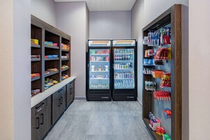 Egy keskeny folyosó, melyben két hűtött vitrin és polcok találhatók, ezeken pedig rágcsálnivalók és italok vannak elhelyezve.
