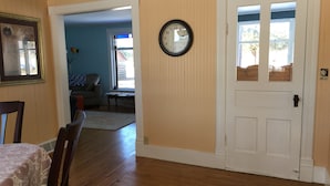 Ein Zimmer mit Holzboden, einer weißen Tür und einer Wanduhr.