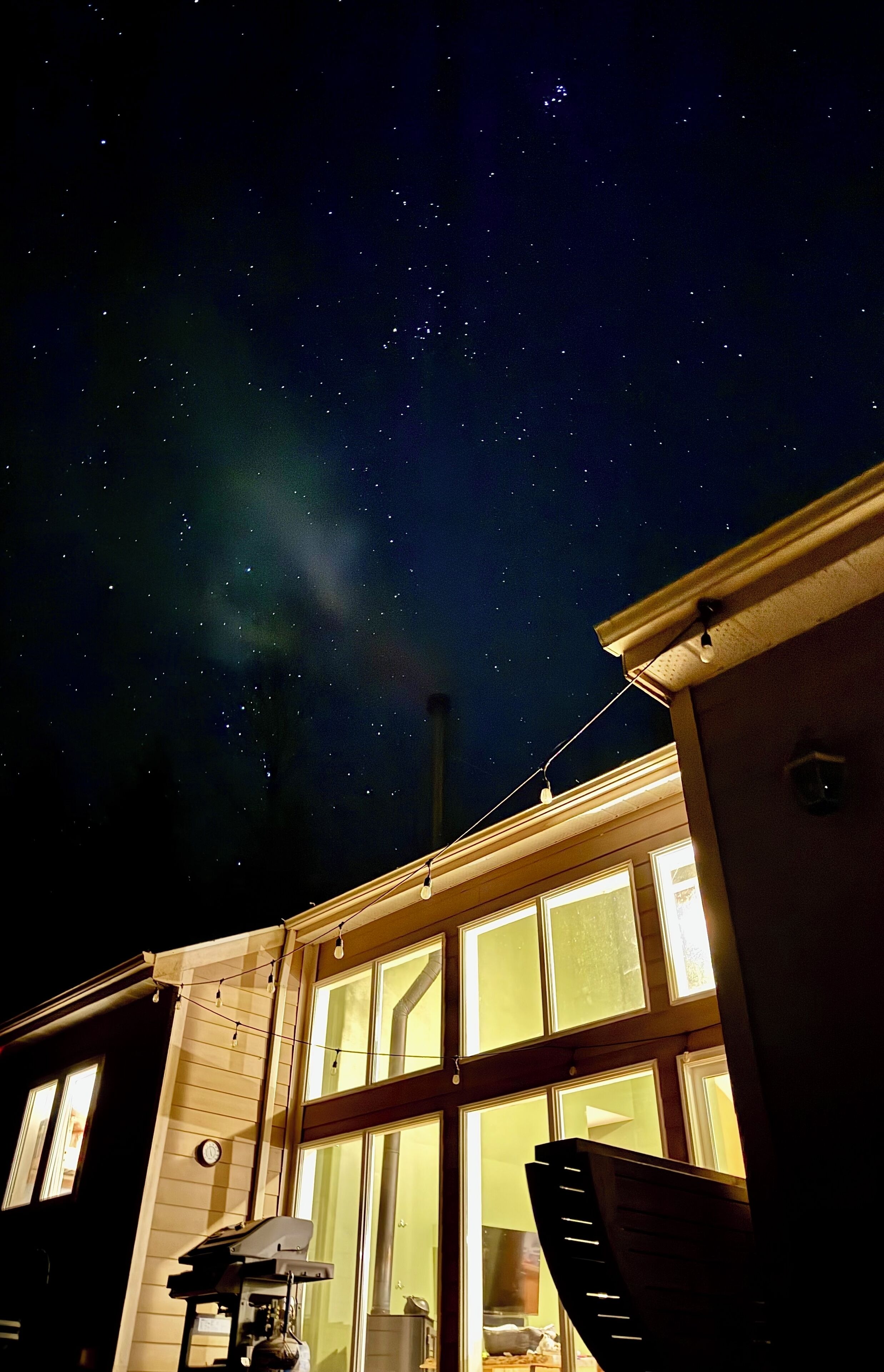 A house with a large window, a chimney, and a string of lights.