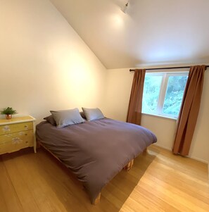 Ein Schlafzimmer mit einem Bett, einem Nachttisch, einem Fenster mit Vorhängen und einer Deckenleuchte.