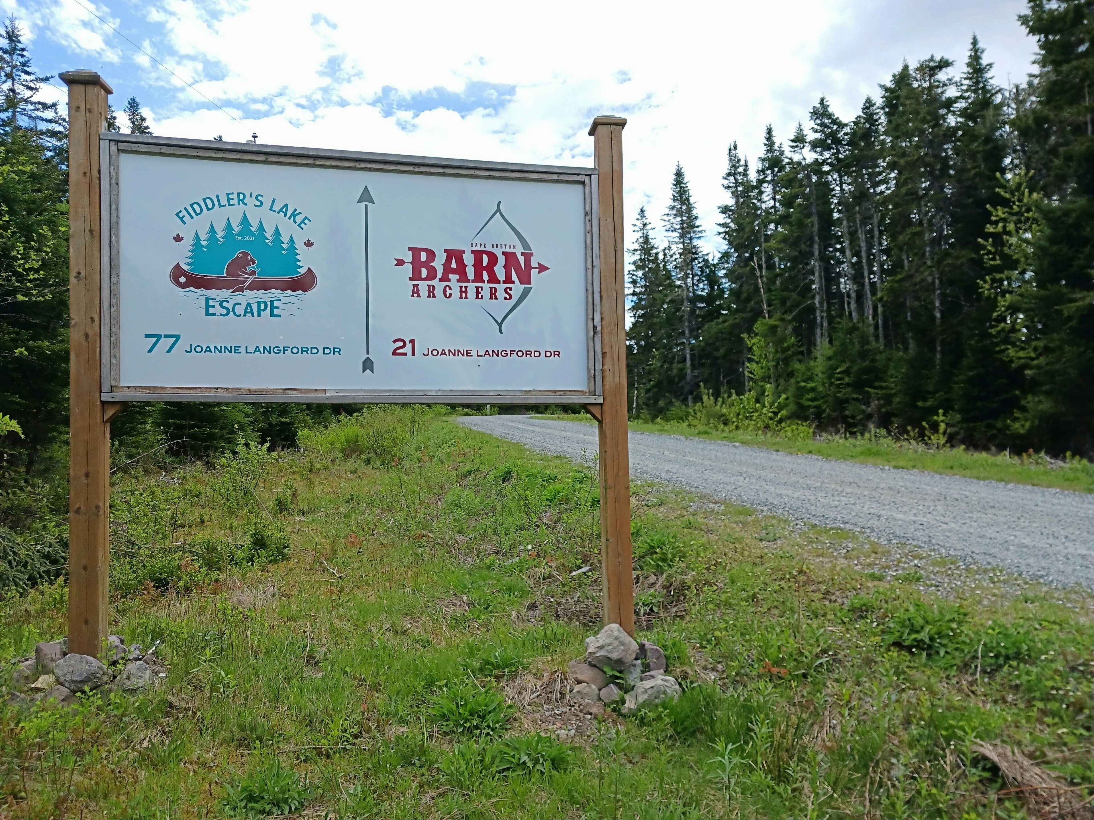 A signboard with directions to Fiddler's Lake Escape and Barn Archers, including street names and distances.