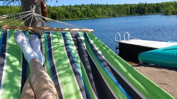 A hammock tied to a tree, a dock, and a lake view.
