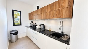 A modern kitchen with white cabinets, a black countertop, and stainless steel appliances.