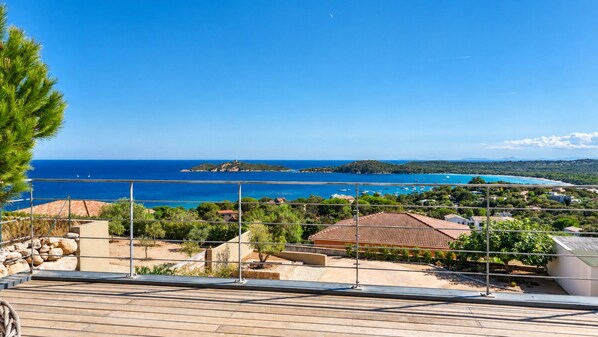 A coastal property with a view of the sea, a small island, and a clear sky.