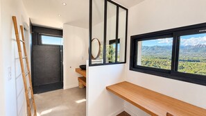 A modern interior with a wooden bench, a mirror, and a window with a mountain view.