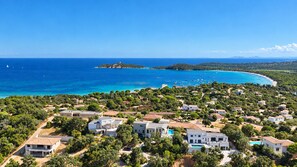 A coastal residential area with houses, a clear blue sea, and a small island in the distance.