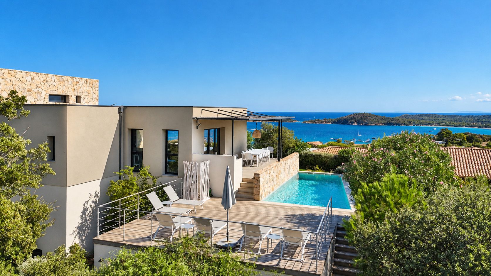 A modern villa with a swimming pool, outdoor seating, and a view of the sea.